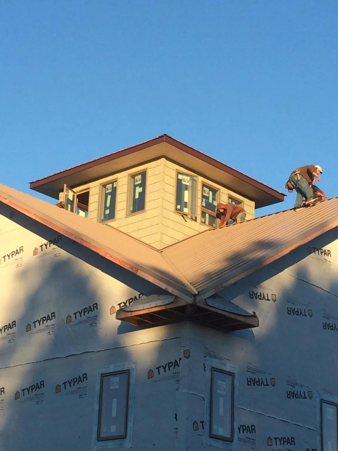 Roofers working around a rooftop cupola on a new metal roof at sunset — Roof Waterproofing in Houston by Roofing Brothers